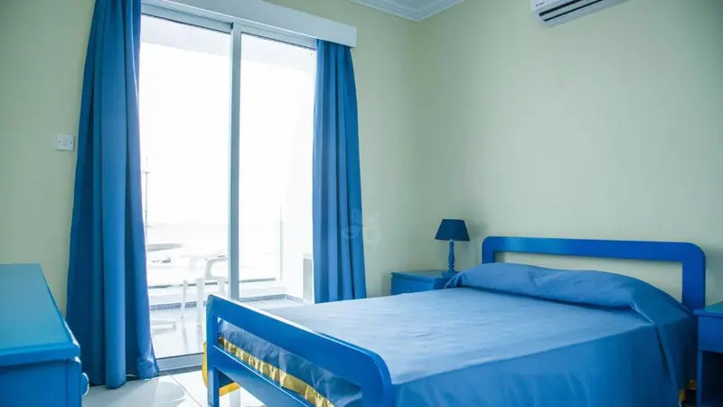 Une chambre lumineuse avec un lit simple donnant sur une terrasse.