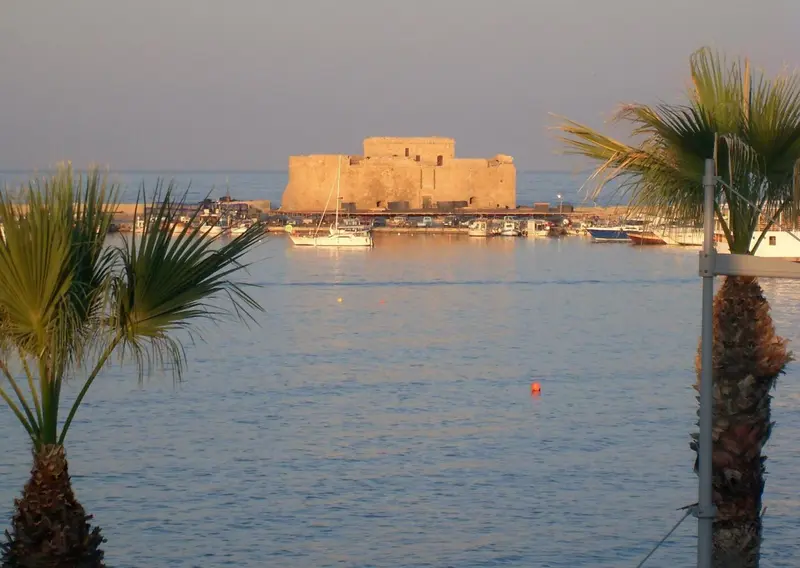 Vue sur un fort en pierre au bord de la mer, avec des bateaux amarrés au port.