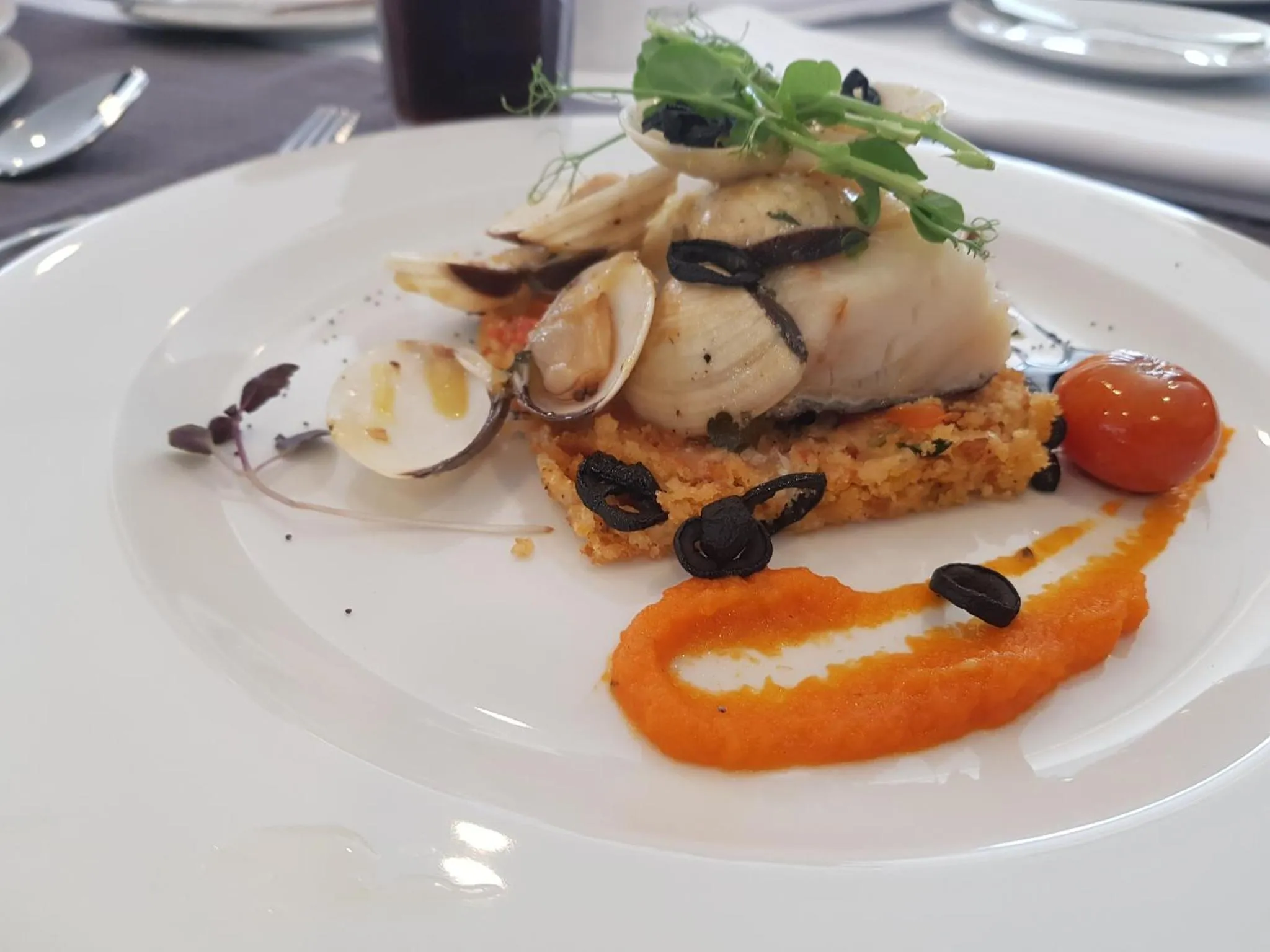 Assiette raffinée de fruits de mer et de légumes disposés avec soin.
