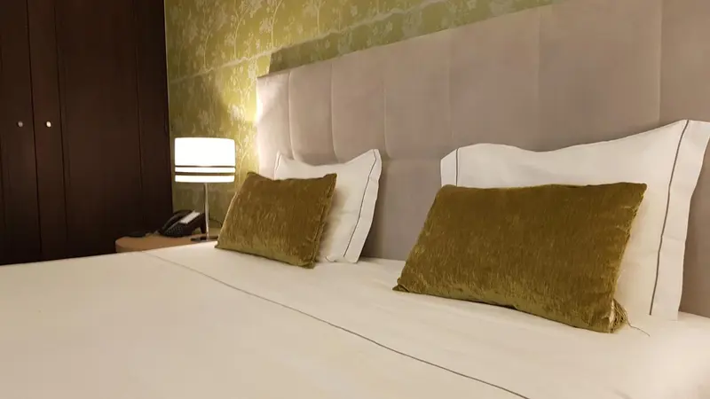 Un lit double avec des oreillers et des coussins verts dans une chambre.