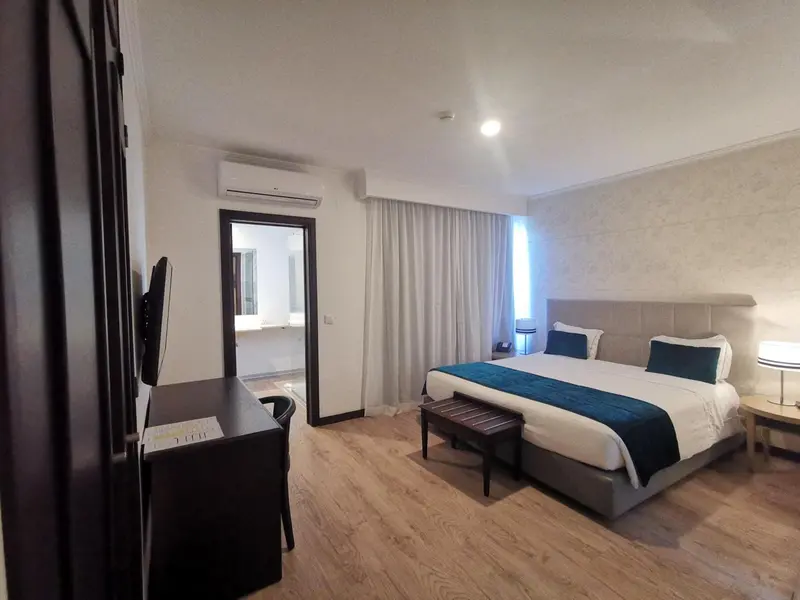 Chambre lumineuse avec un lit double et un espace bureau.