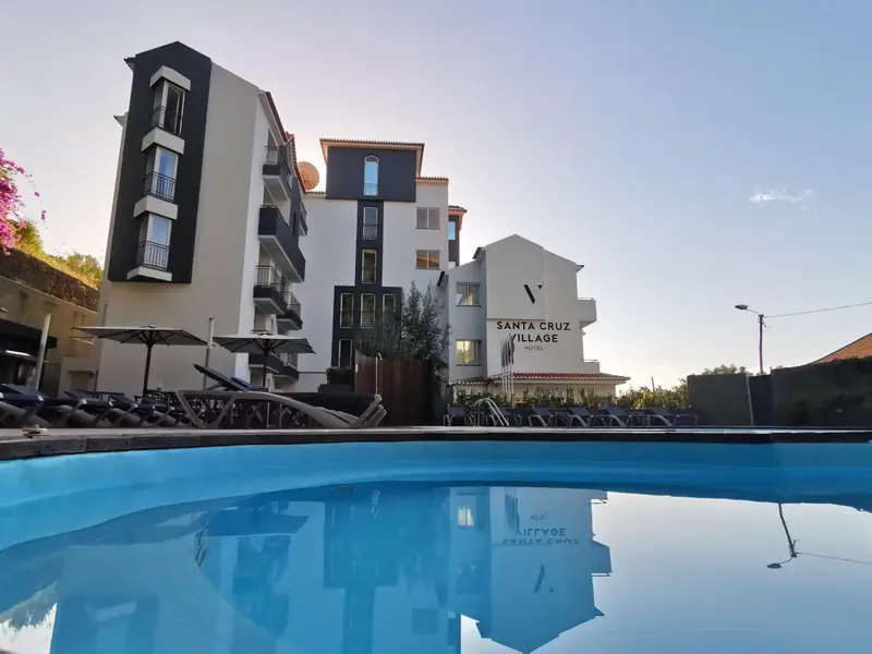 Vue d'un bâtiment blanc et d'une piscine turquoise sous un ciel bleu.