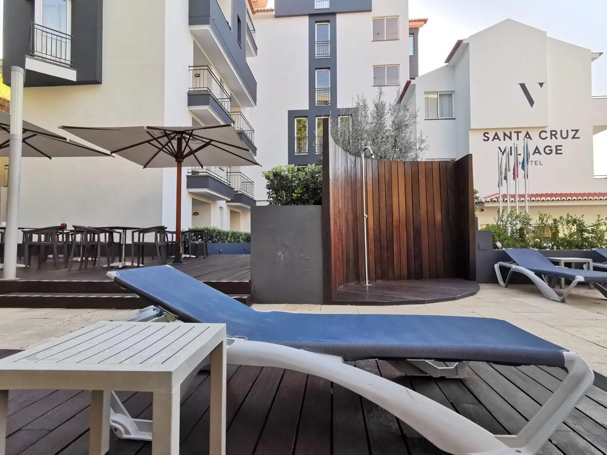Transats bleus disposés sur une terrasse en bois près d'une piscine.
