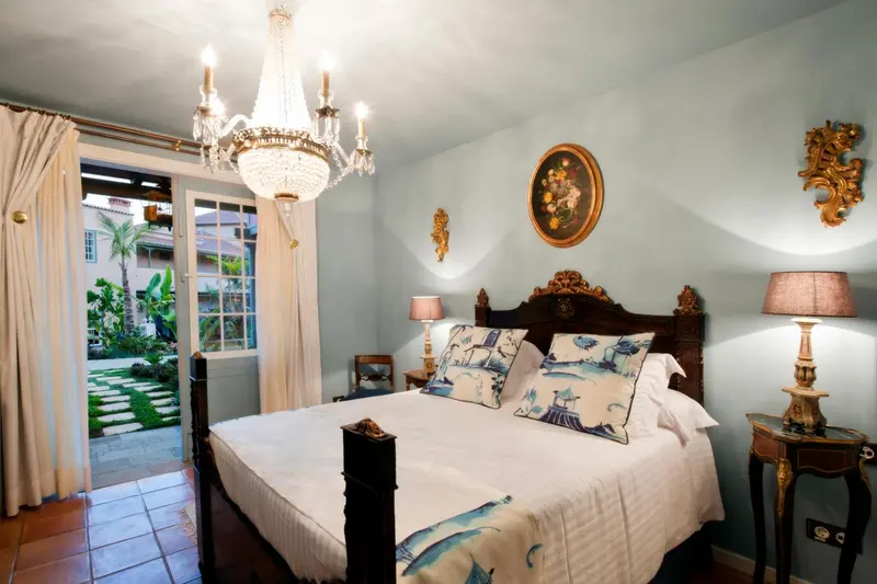 Une chambre lumineuse avec un grand lit à baldaquin et un lustre décoratif.