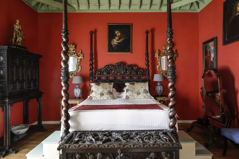 Une chambre à coucher avec un grand lit à baldaquin sculpté et des tableaux.