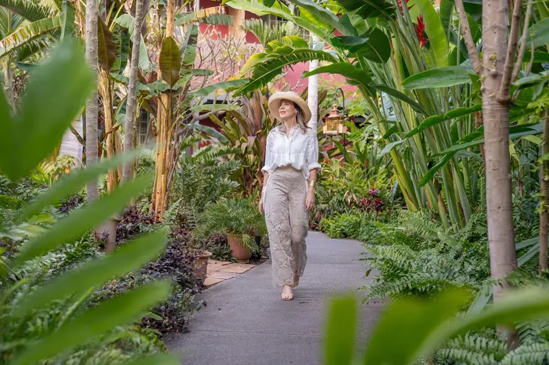 Une promenade bordée de végétation luxuriante mène à un bâtiment rouge.