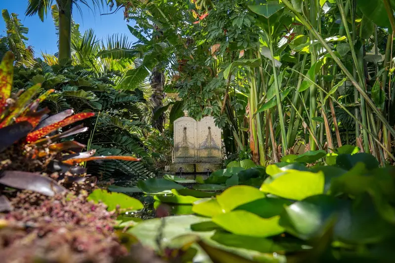 Une fontaine en pierre se trouve au milieu d'une végétation luxuriante et colorée.