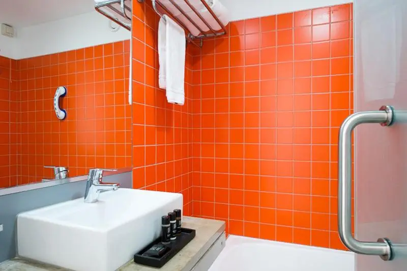 Une salle de bain moderne avec des carreaux orange et un lavabo blanc.