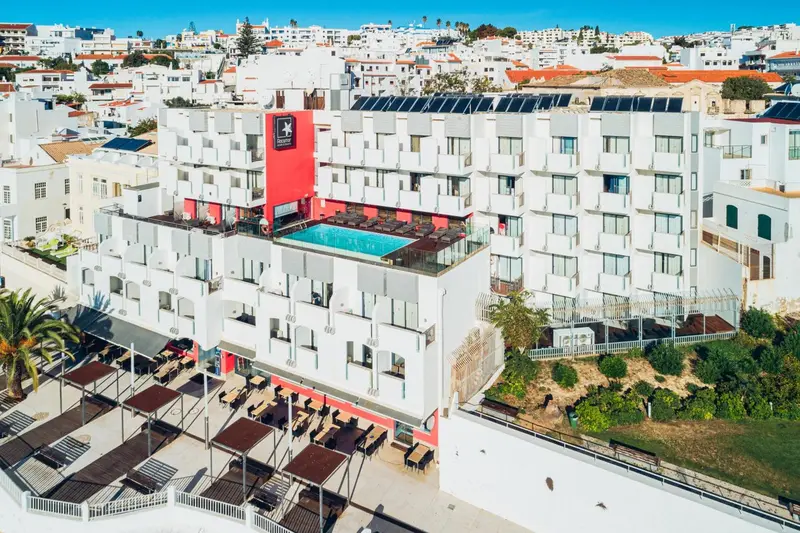 Vue aérienne d'un complexe hôtelier blanc avec une piscine et des transats.