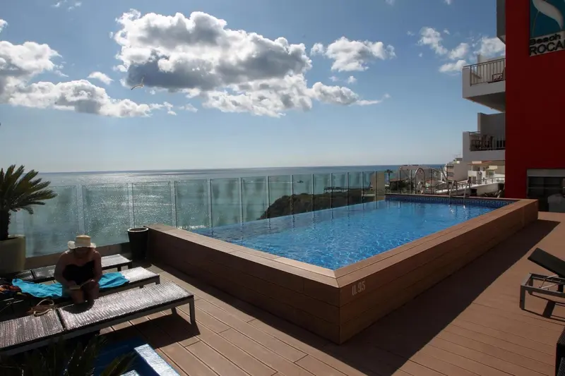 Piscine à débordement avec terrasse et vue sur la mer.