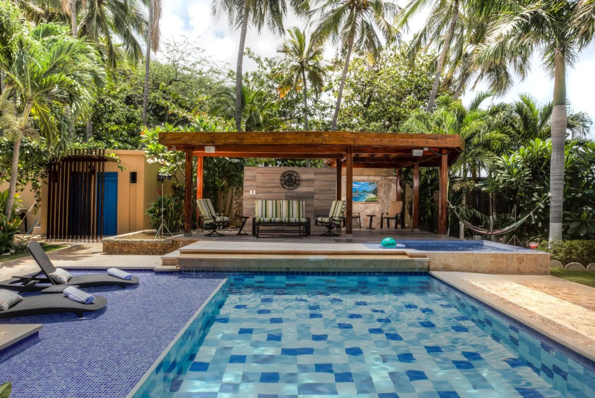 Espace de détente extérieur avec piscine et salon ombragé.