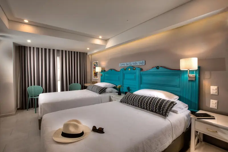 Chambre lumineuse avec deux lits simples et une décoration colorée.