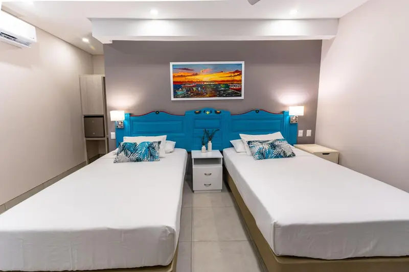 Une chambre lumineuse avec deux lits simples et une décoration colorée.