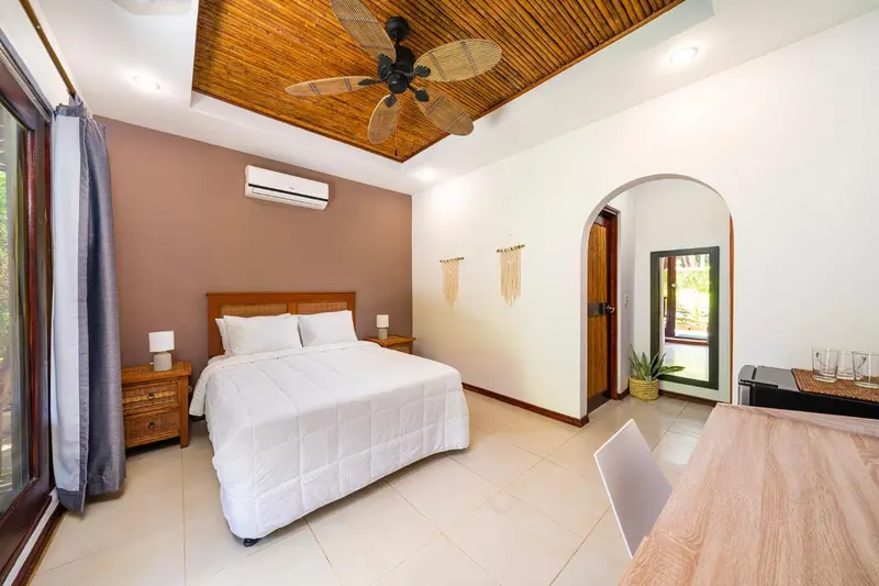 Une chambre lumineuse avec un lit blanc et un coin repas.