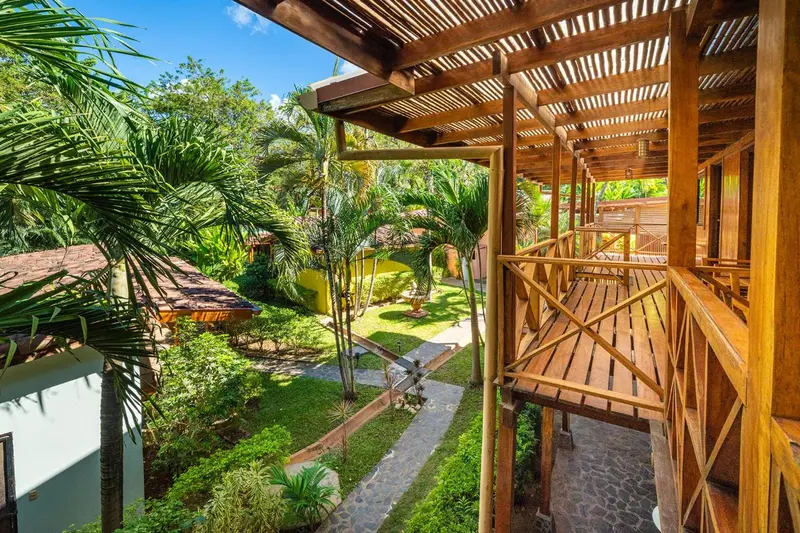 Terrasse en bois avec vue sur une cour verdoyante et des bâtiments.