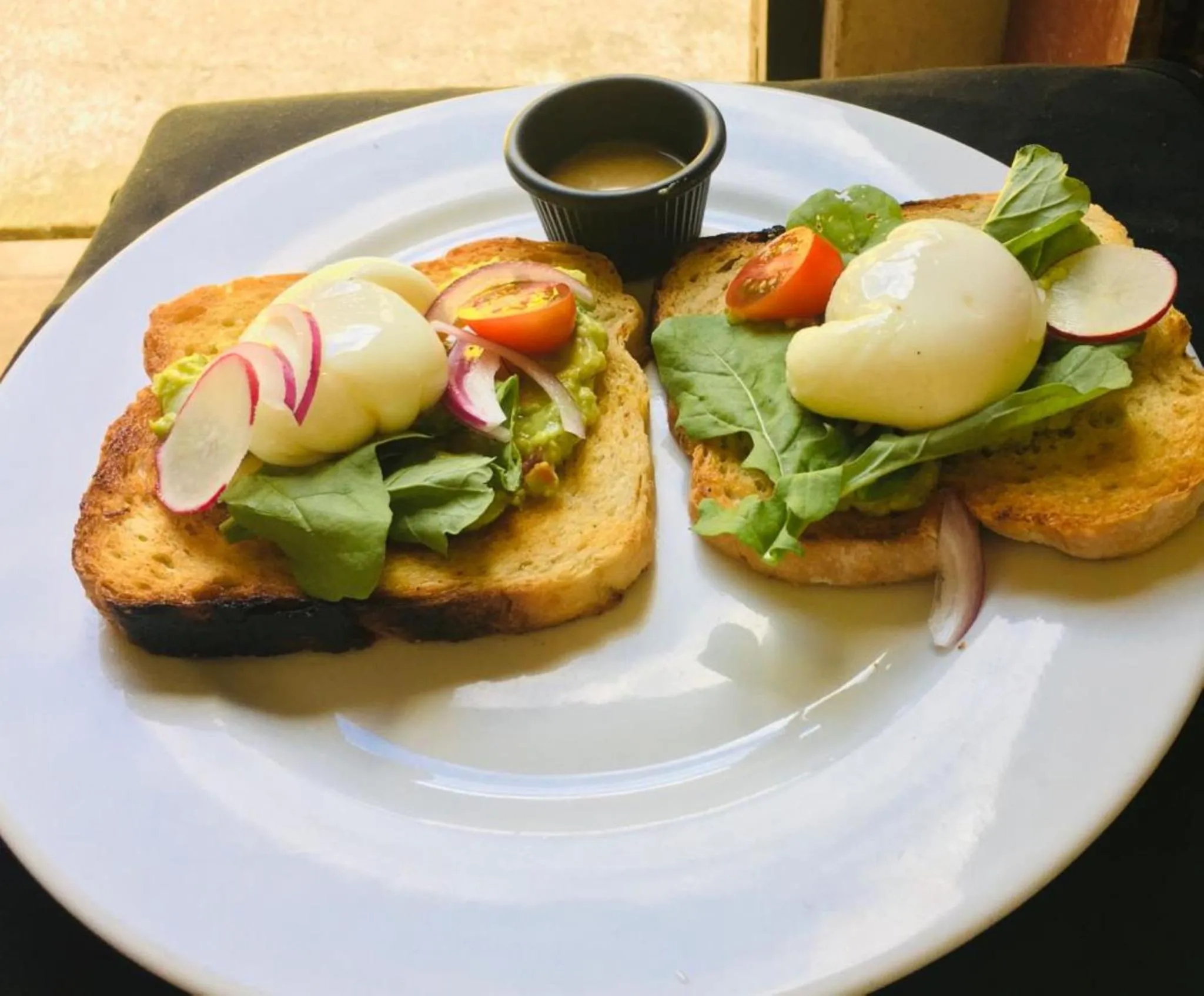 Assiette de toasts garnis d'avocat, d'oeufs pochés et de légumes.
