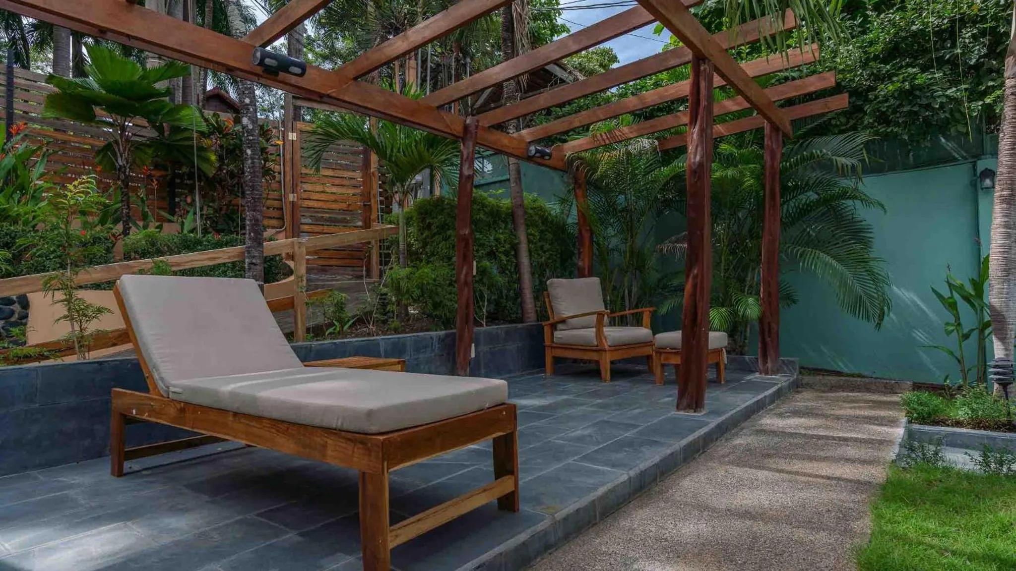Deux transats en bois sur une terrasse ombragée par une pergola.