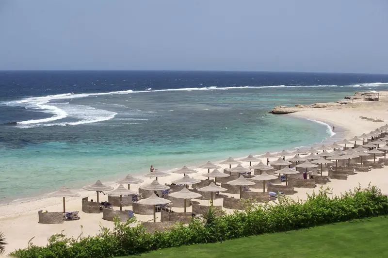 Vue aérienne d'une plage avec des parasols et une mer turquoise.