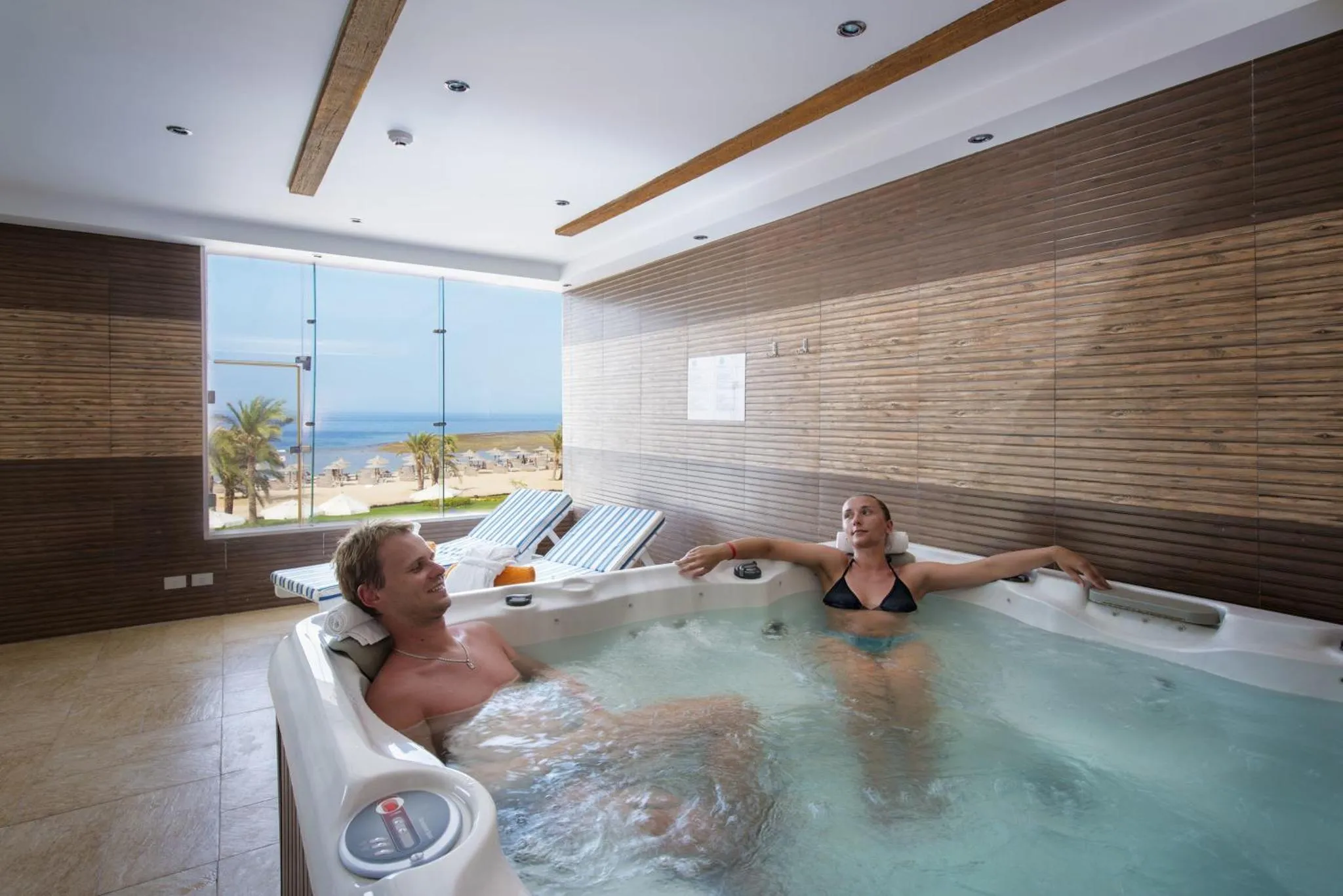 Un couple se détend dans un jacuzzi intérieur avec vue sur la mer.