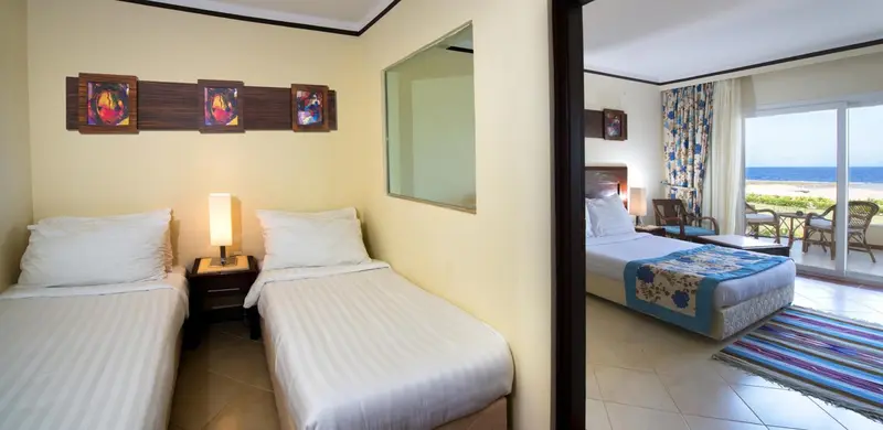Chambre lumineuse avec deux lits simples et vue sur la mer.