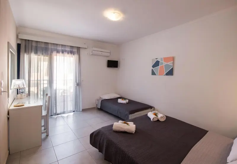 Une chambre lumineuse avec deux lits simples et un accès à une terrasse.