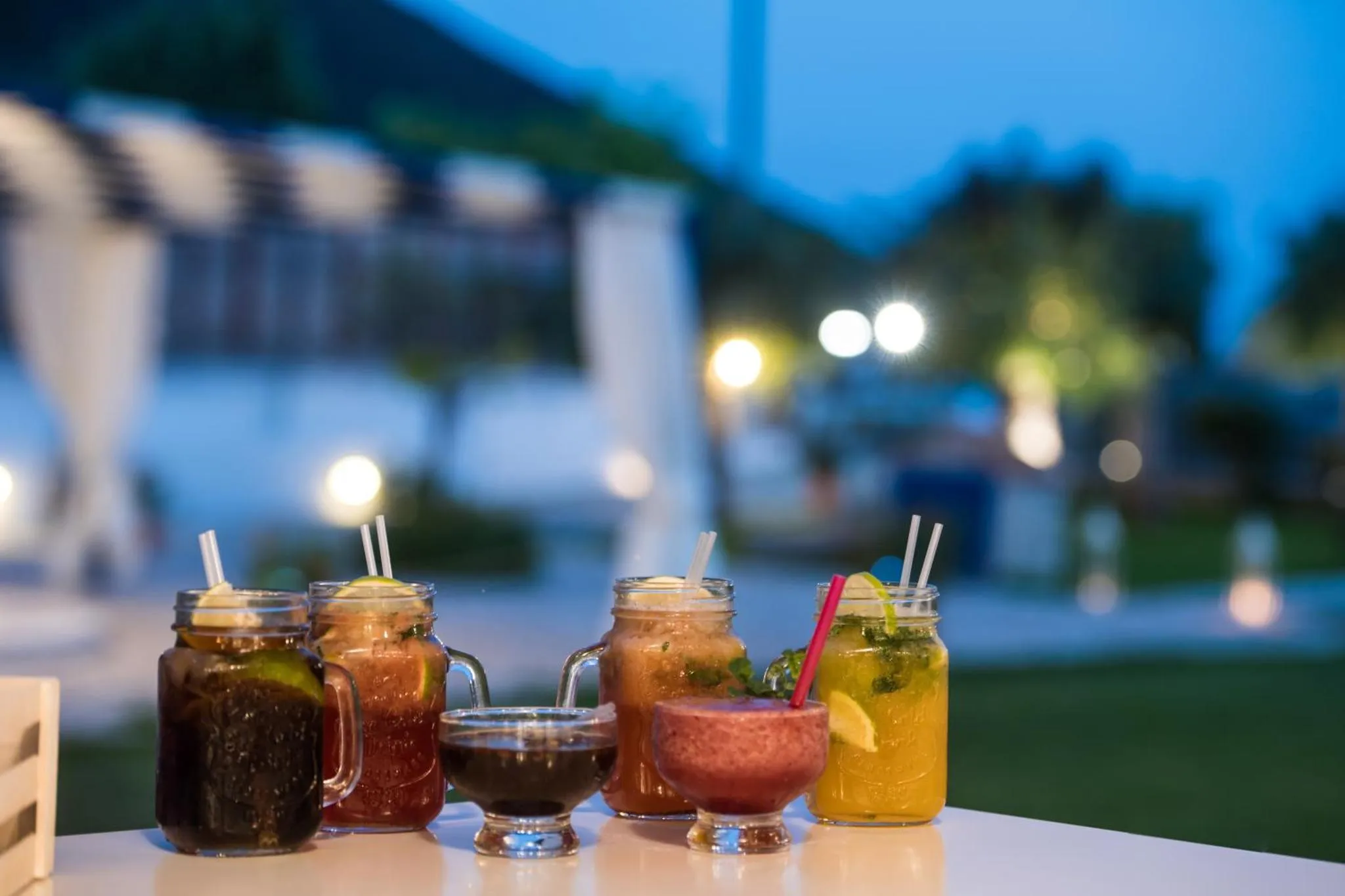 Des boissons colorées sont présentées sur une table en extérieur.