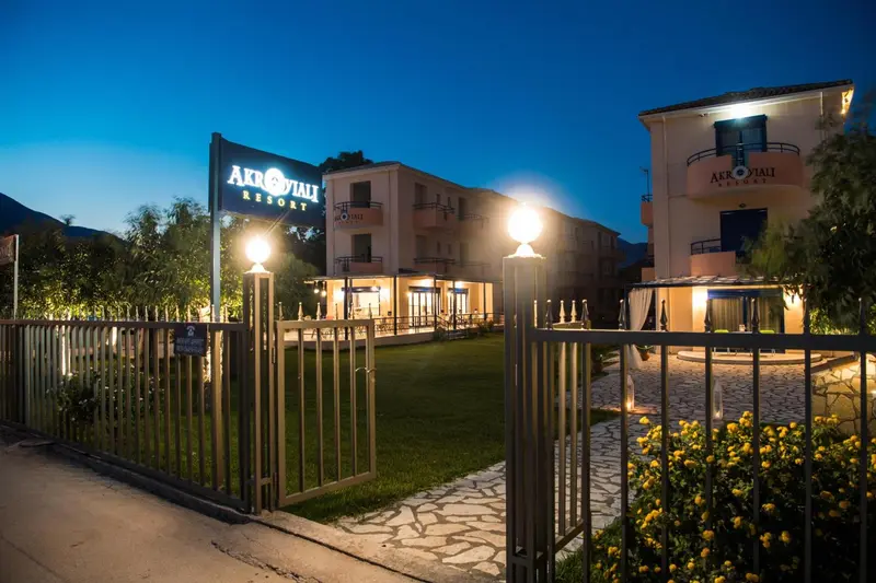 Façade d'un bâtiment éclairé la nuit avec un jardin soigné.