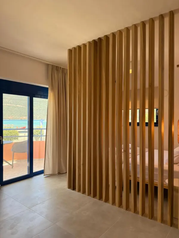 Une chambre lumineuse avec une séparation en bois et une vue sur la mer.