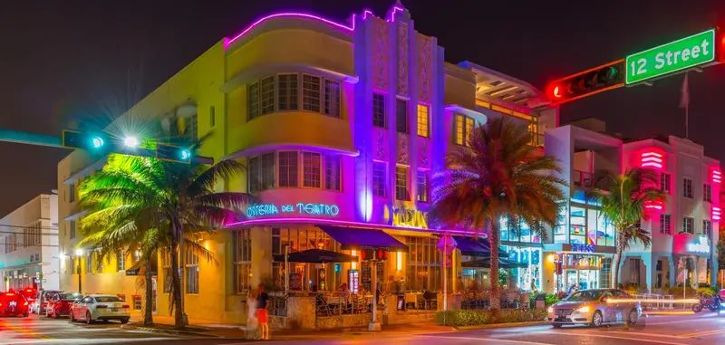 Façade d'un bâtiment illuminé aux couleurs vives dans une rue urbaine.