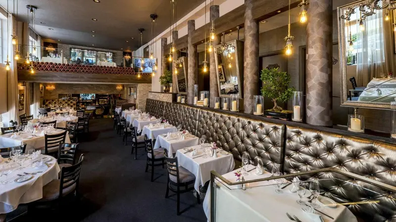 Une salle de restaurant élégante avec des tables dressées et un éclairage tamisé.
