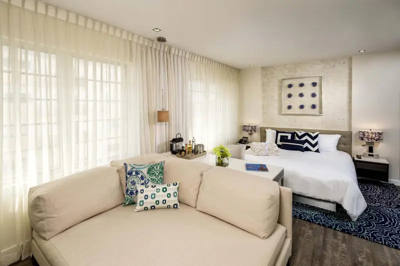 Une chambre lumineuse avec un canapé et un lit décoré de coussins.