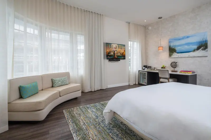 Une chambre lumineuse avec un canapé incurvé et un grand lit.