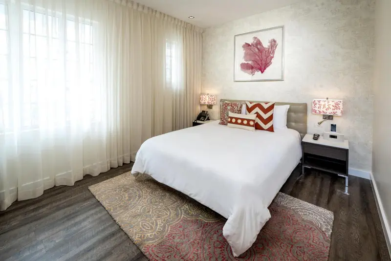 Une chambre lumineuse avec un grand lit recouvert de coussins décoratifs.