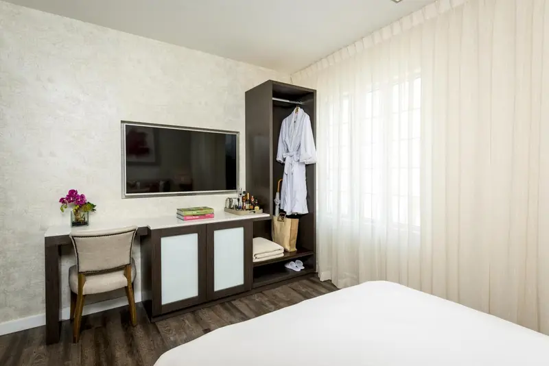 Une chambre lumineuse avec un bureau et un téléviseur fixé au mur.