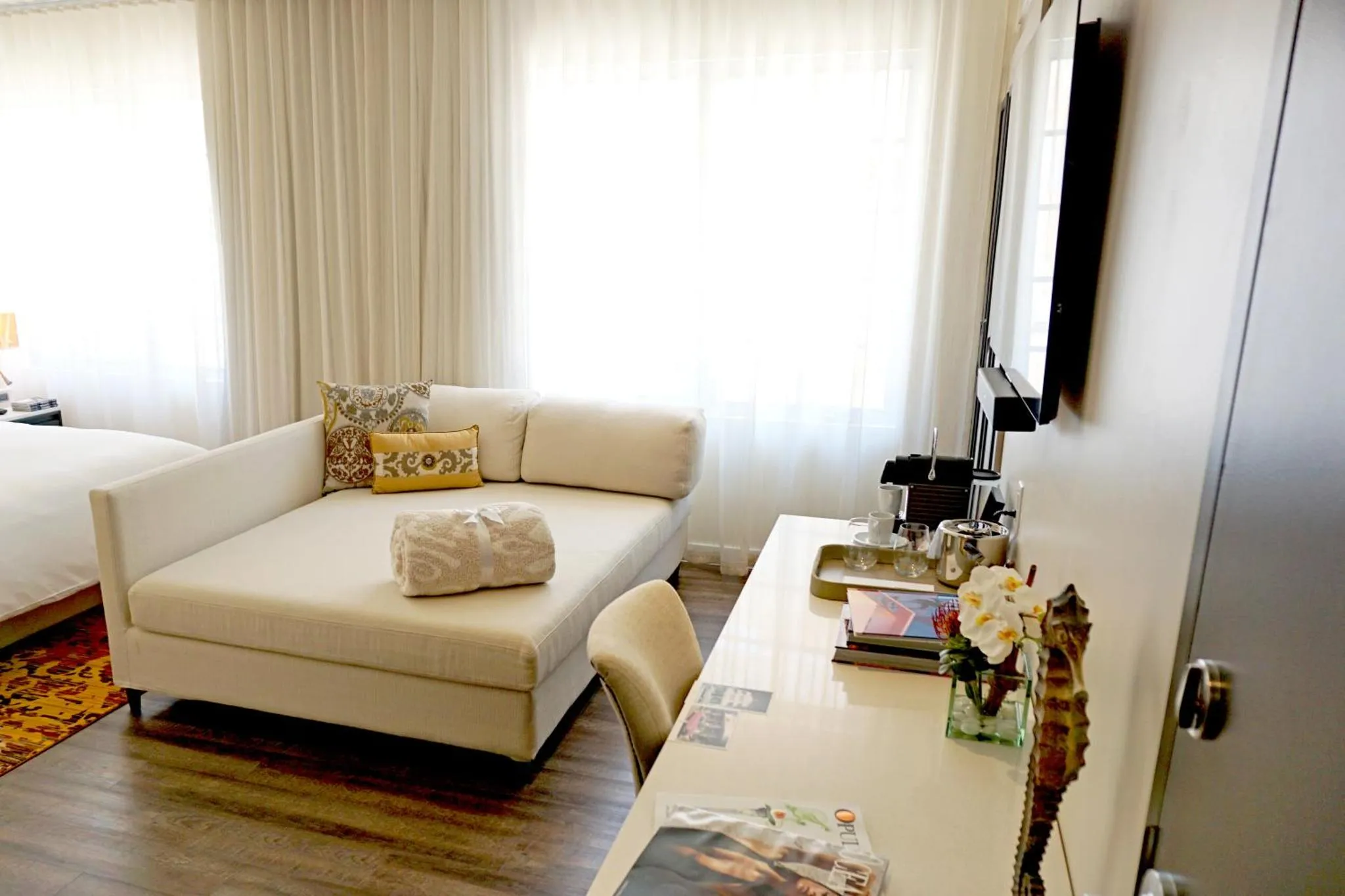 Espace de détente avec canapé et bureau dans une chambre lumineuse.