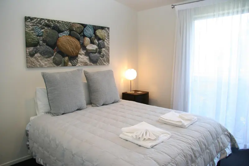 Une chambre lumineuse avec un lit double et une décoration sobre.