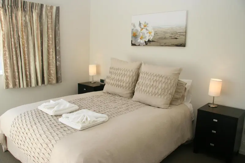 Une chambre avec un grand lit recouvert d'une courtepointe et de coussins.