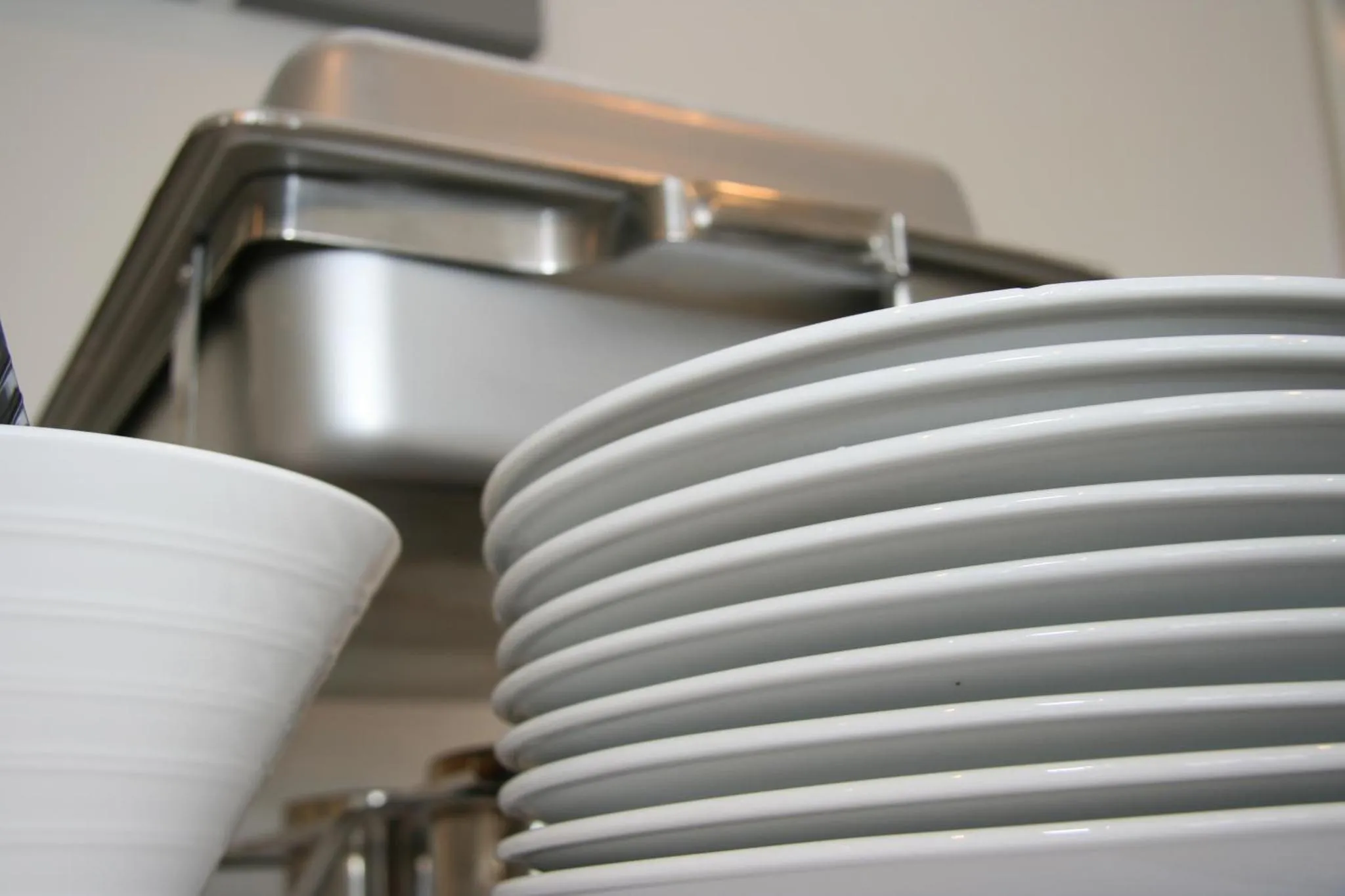 Assiettes blanches empilées sur un comptoir en inox.