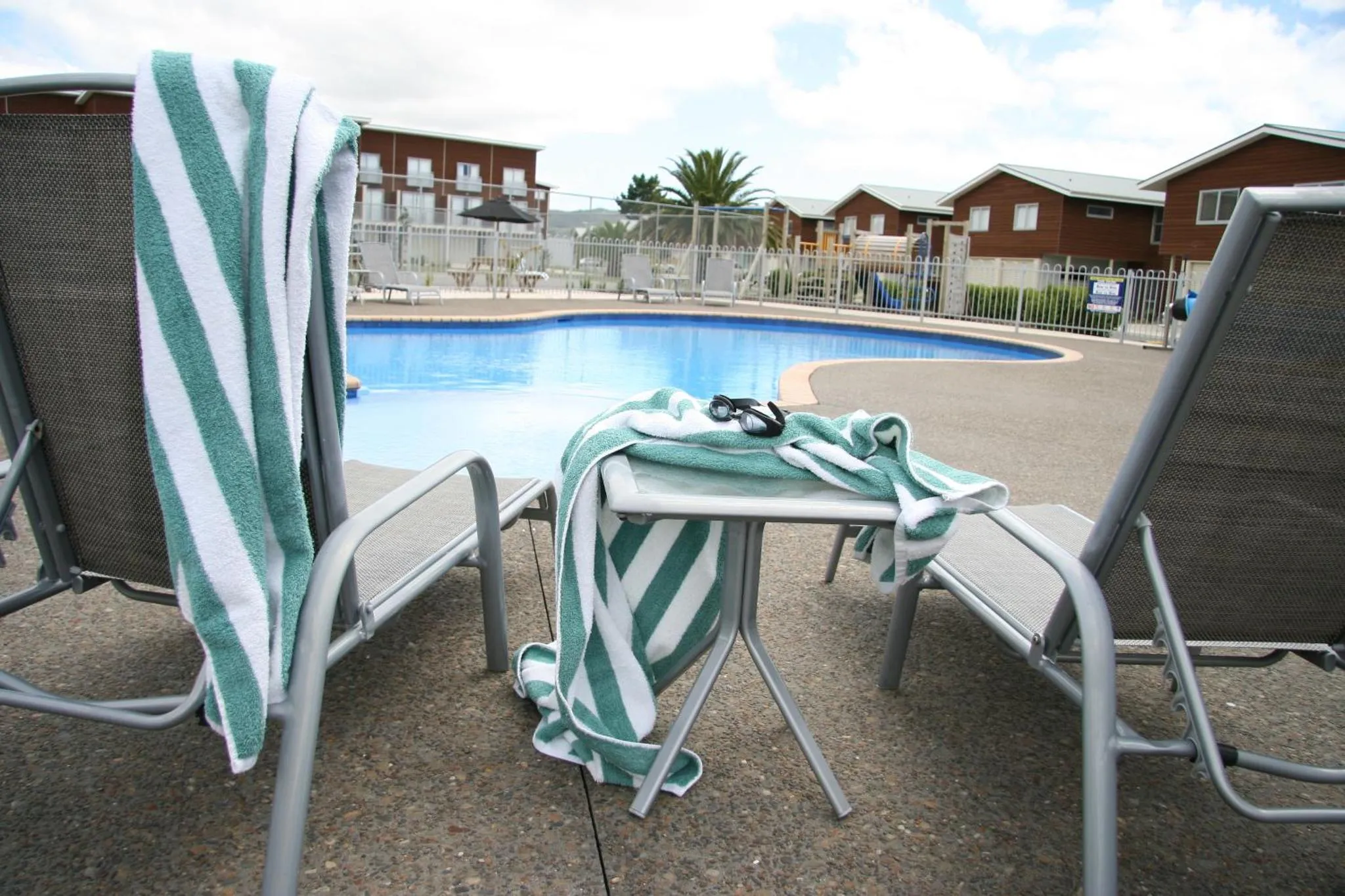 Deux transats avec des serviettes près d'une piscine ensoleillée.