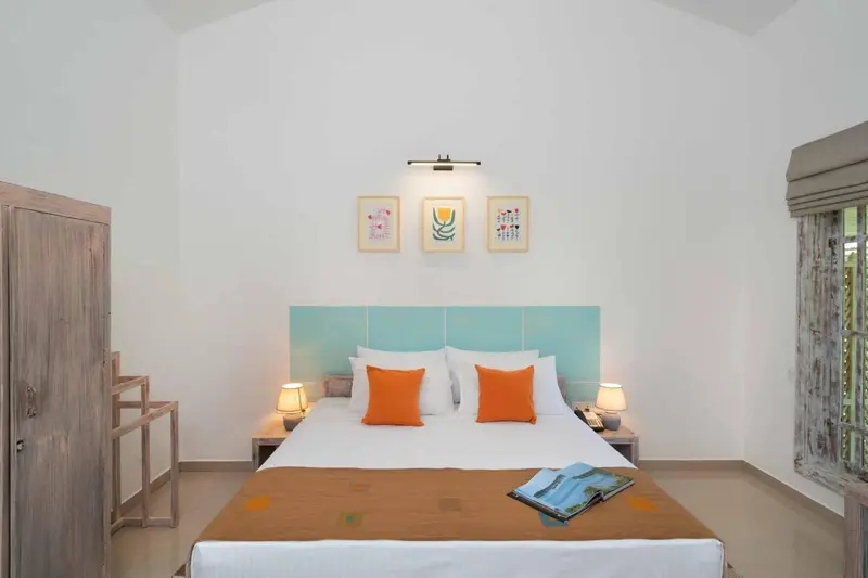 Une chambre lumineuse avec un grand lit et des coussins orange.