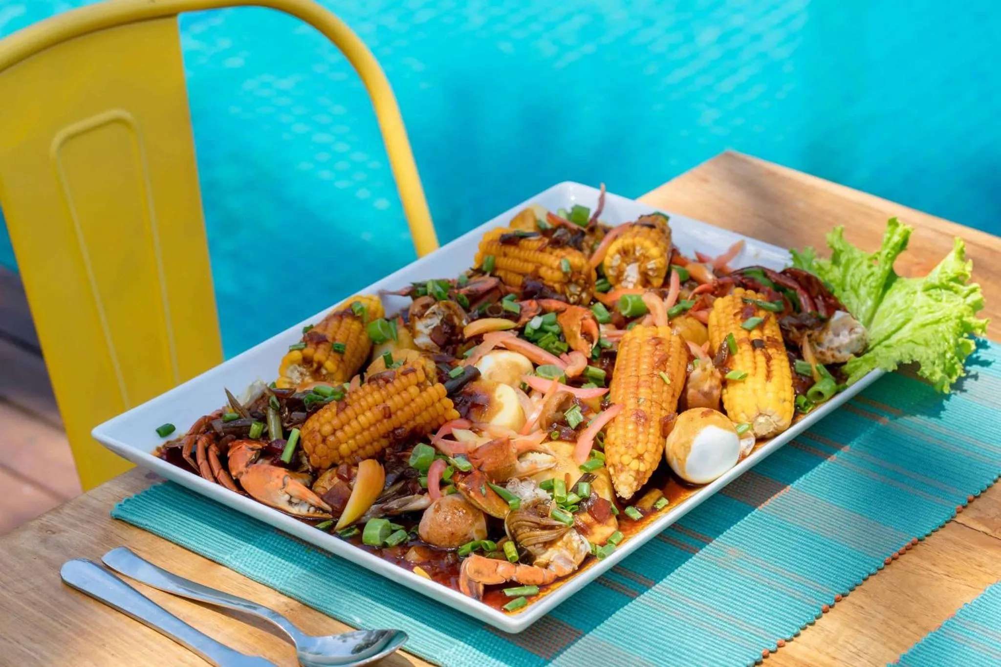 Assiette généreuse de fruits de mer et de légumes servis sur une table en extérieur.