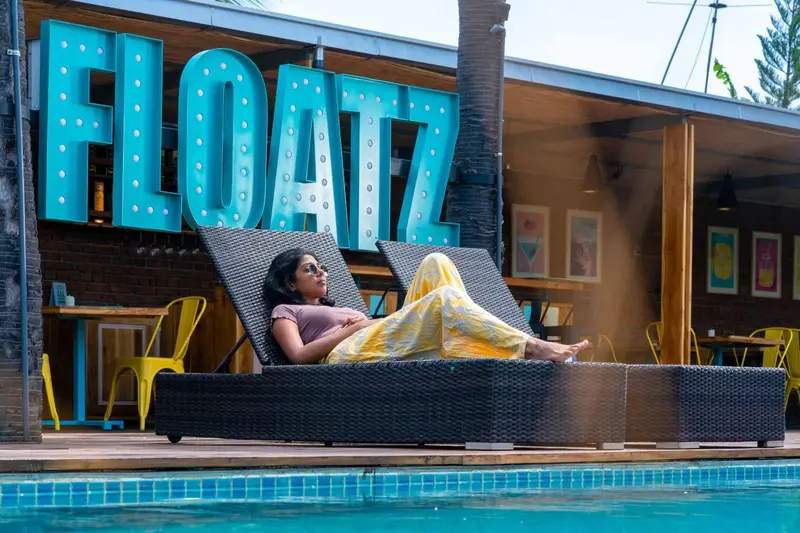 Une femme se relaxe sur des transats au bord d'une piscine.