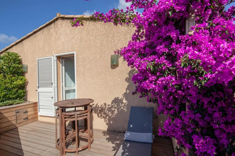 Façade d'un bâtiment ornée de bougainvillées et d'une terrasse en bois.