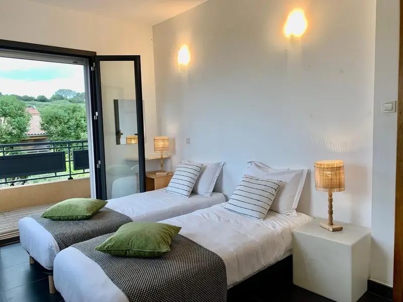 Une chambre lumineuse avec deux lits simples et une vue sur l'extérieur.