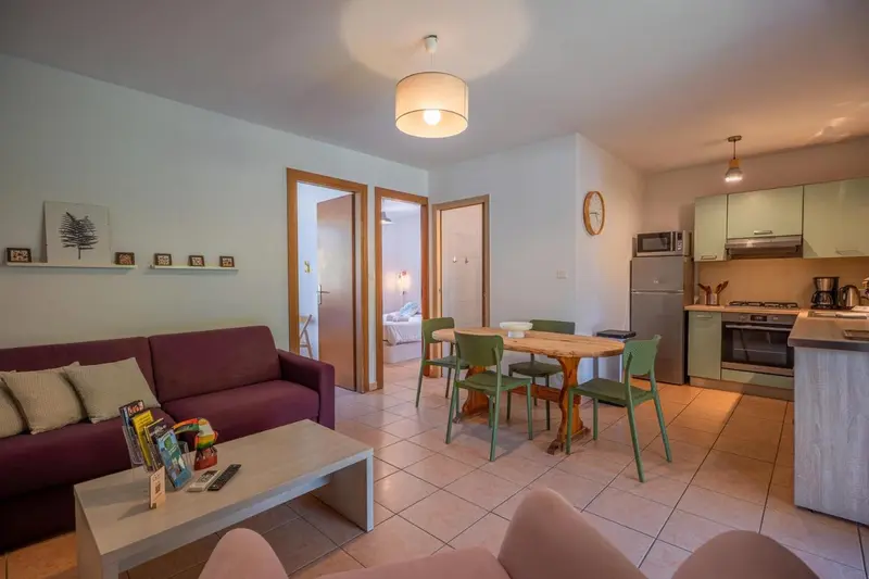 Espace de vie lumineux avec canapé, table à manger et cuisine équipée.