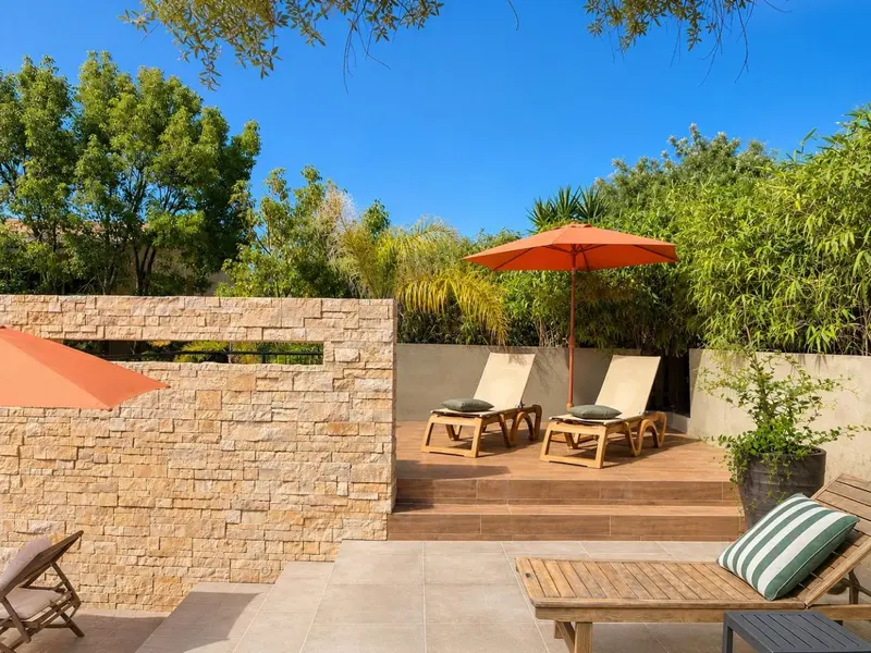 Transats orange et verts sur une terrasse en bois ensoleillée.