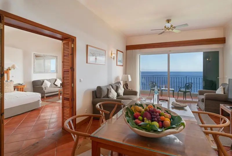 Espace de vie lumineux avec canapés, table basse et vue sur la mer.