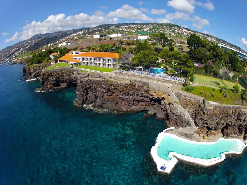 Vue aérienne d'un complexe hôtelier sur une côte rocheuse avec une piscine.