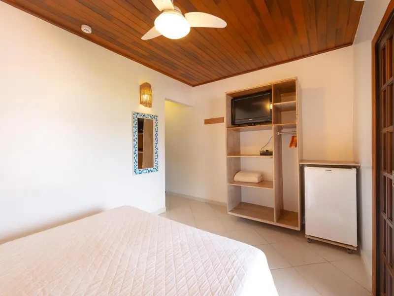 Une chambre lumineuse avec un lit recouvert d'une courtepointe blanche et un meuble de rangement.
