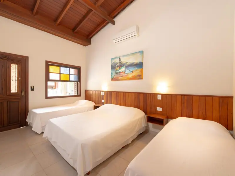 Chambre lumineuse avec deux lits simples et une décoration murale.